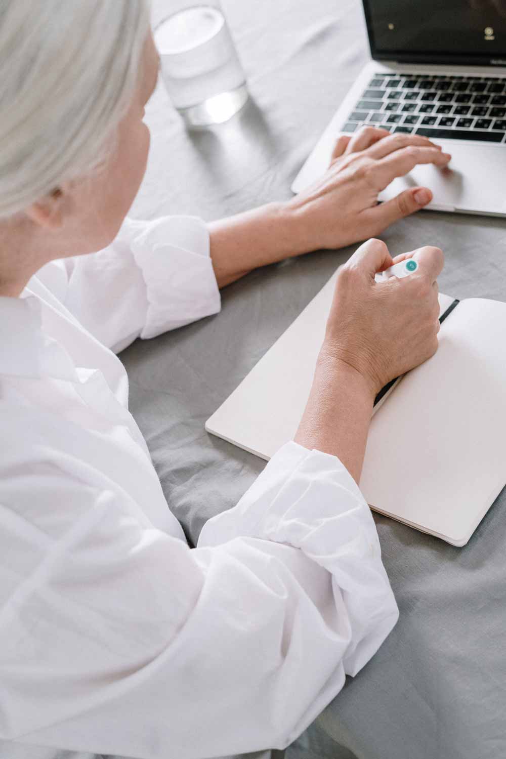 white-haired woman writes in a notebook